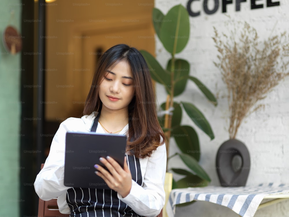 Portrait of young beautiful waitress taking an order on digital tablet in restaurant