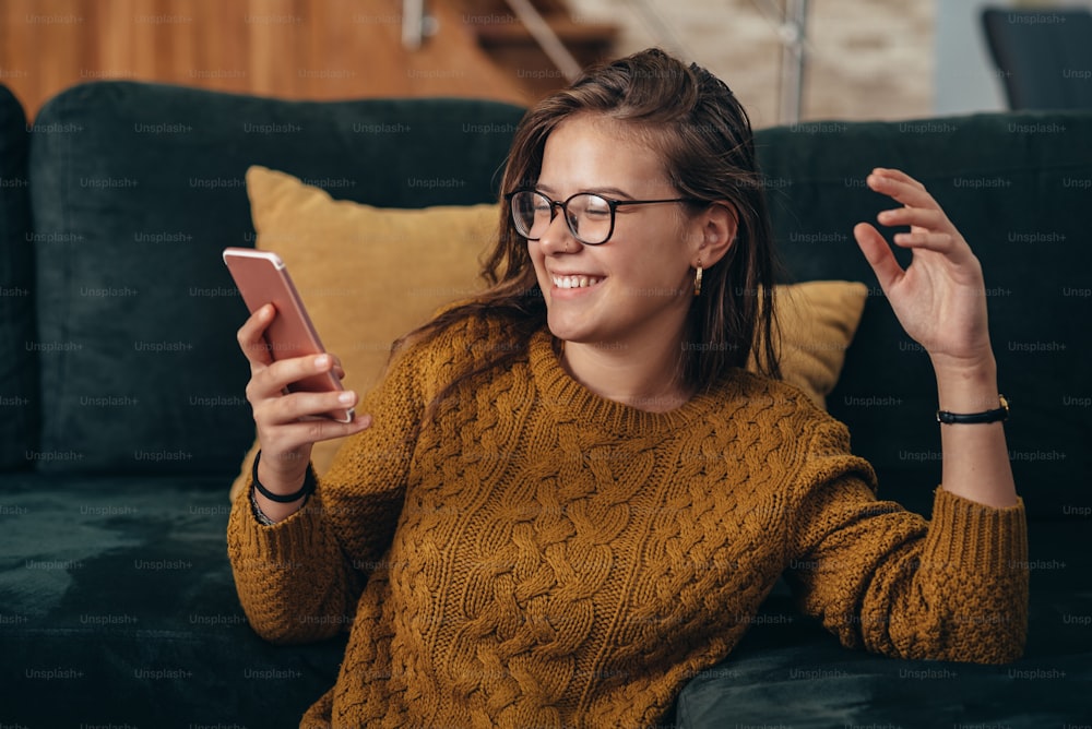 Shot of a happy young woman relaxing on the living room floor at home while using a smartphone