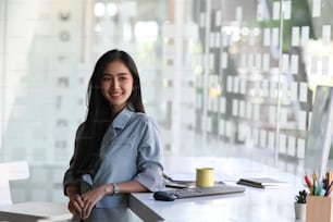 Portrait of cheerful businesswoman standing near her workplace.