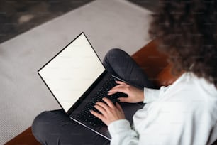 フリーランスや学生の女の子が、画面が空白のノートパソコンを見ている。ラップトップで電子メールを書いたり、インターネットで情報を検索したり、買い物をしたり、オンラインでチャットしたりする若い成人女性のトリミングされたビュー