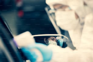 Donna asiatica guida attraverso i test Covid-19 con il personale medico DPI, temperatura dei test COVID durante il check-in delle auto