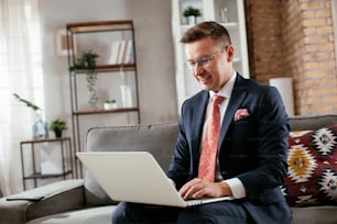 Jeune homme d’affaires travaillant avec un ordinateur portable au bureau. Homme d’affaires assis sur un canapé en train de passer un appel vidéo