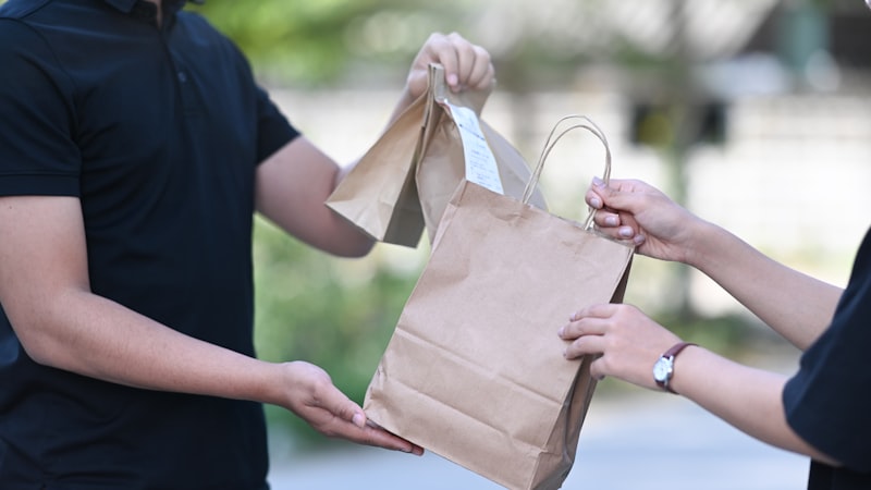 Delivery driver handing a bag to a customer at the door