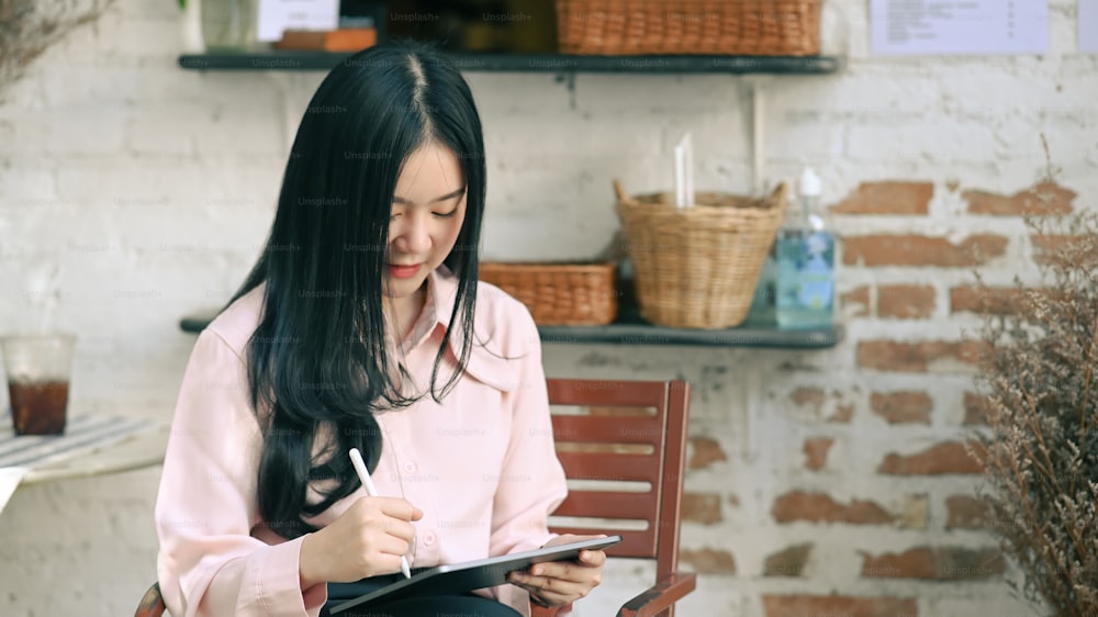 Joven diseñadora usando lápiz óptico dibujando en una tableta digital mientras está sentada en un lugar de trabajo cómodo.