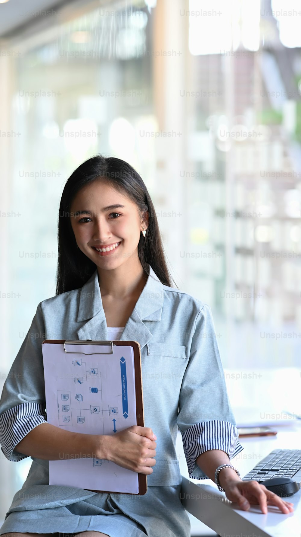 Retrato de una mujer de negocios sonriente sosteniendo documentos y sonriendo a la cámara.