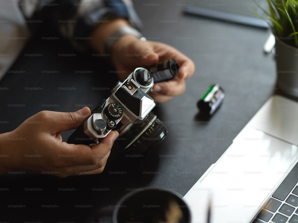 Vista de cerca de las manos del fotógrafo usando la cámara en la mesa de trabajo con suministros en el estudio