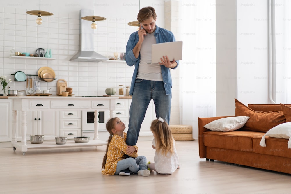 Gestresster Vater, der von zu Hause aus mit Kindern arbeitet. Homeschooling, zu Hause bleiben, Social Distancing während der Coronavirus-Quarantäne-Isolation, freiberuflicher Job