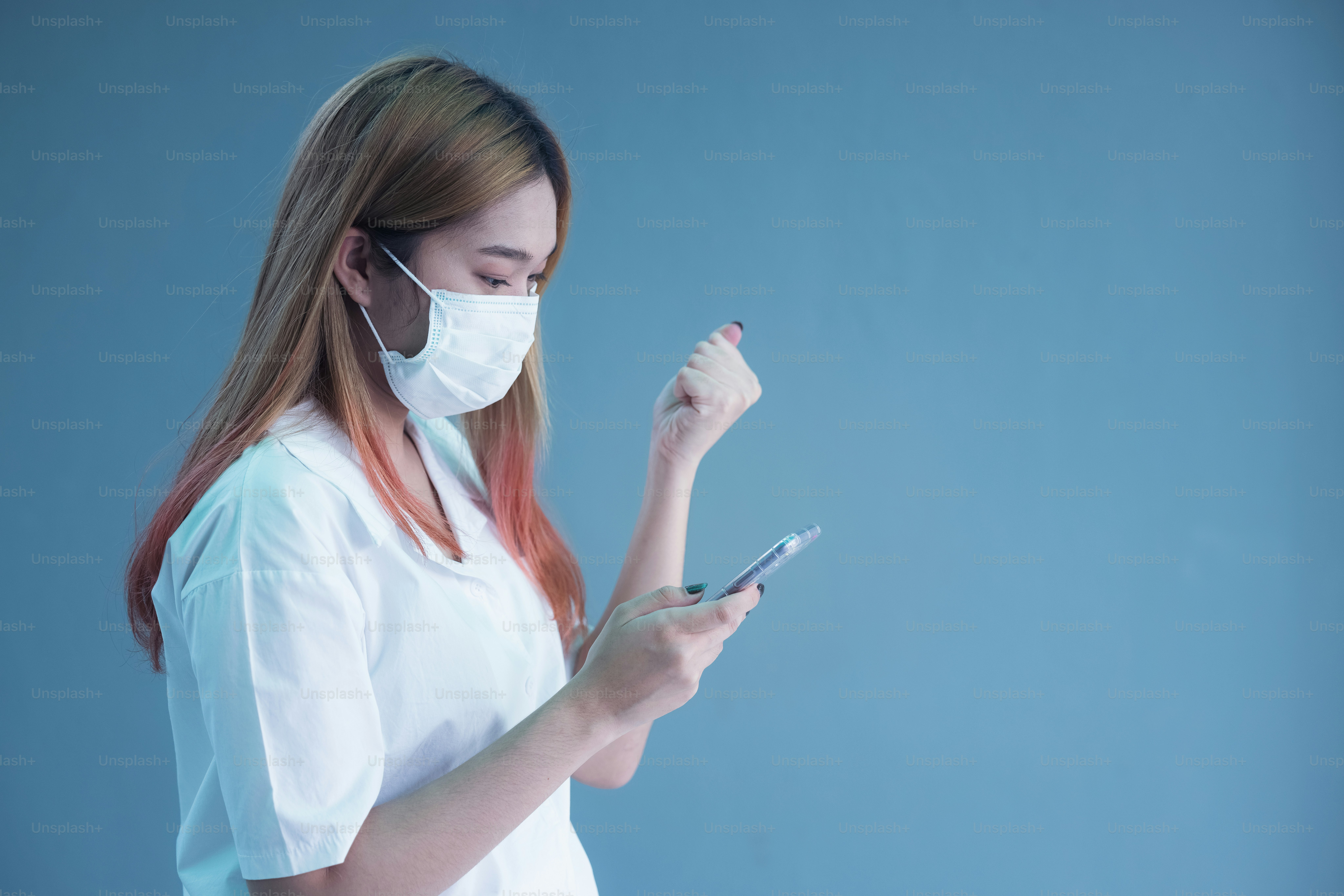 Young woman wearing mask using smartphone over isolated background very happy pointing with hand