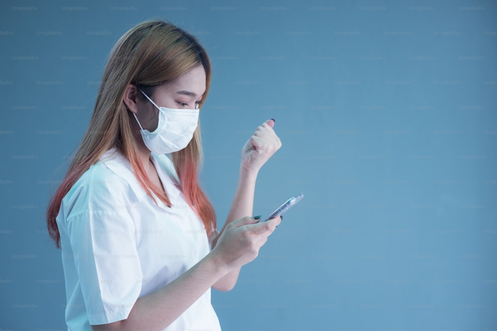 Giovane donna che indossa la maschera usando lo smartphone su sfondo isolato molto felice che indica con la mano