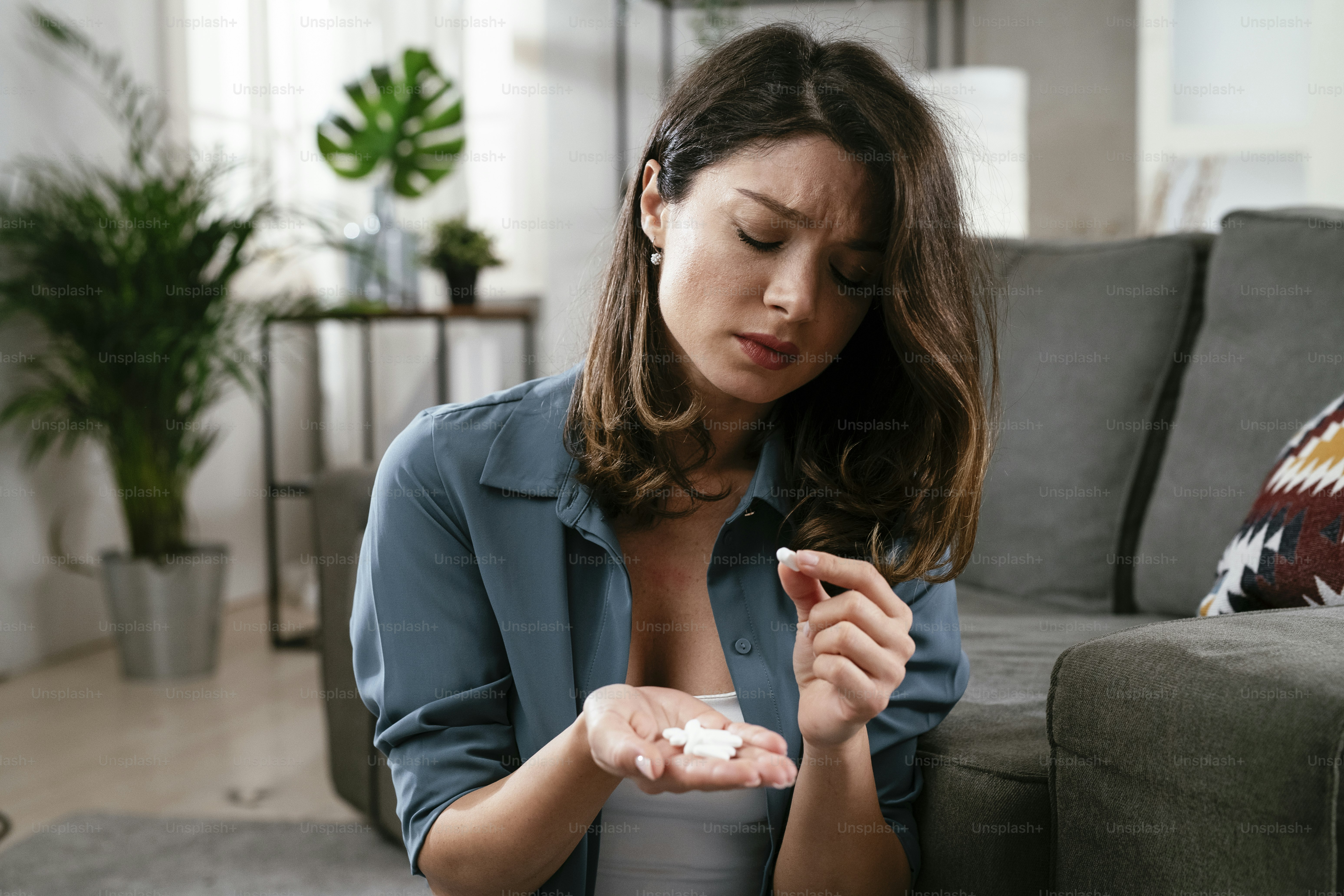 Traurige unglückliche depressive Frau hält eine Pille in der Hand. Verzweifelte junge Frau mit einer Handvoll Pillen