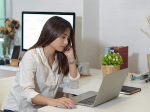 Side view of female office worker work from home with laptop and computer in home office room