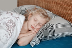 Bonito adorável menina loira caucasiana pequena dormindo no travesseiro na cama em casa. Doces sonhos e vibrações de cama. Rotina diária no início da manhã. Vida doméstica autêntica e sincera.