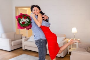 自宅で美しい若いカップル。ハグしたり、キスをしたり��、一緒に過ごしたりしながら、赤いバラで聖バレンタインデーを祝います