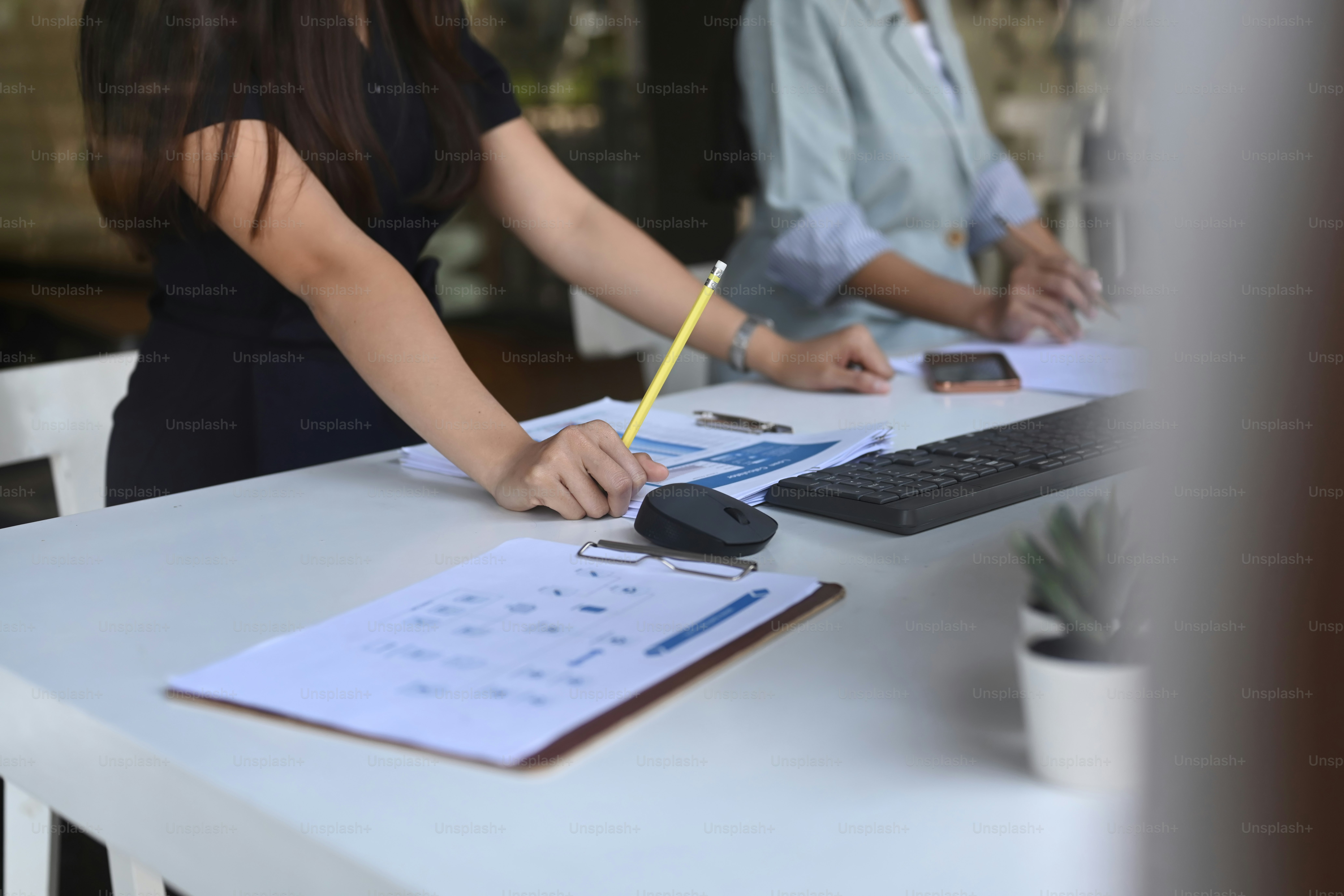 Plan recadré d’une femme d’affaires analysant des données commerciales sur un bureau blanc.