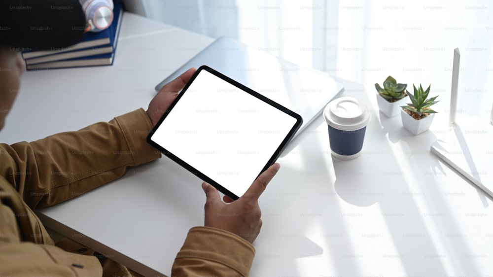 Ausschnittaufnahme eines jungen Mannes, der ein digitales Tablet verwendet, um das Internet oder die drahtlose Verbindung zu Hause zu verbinden.
