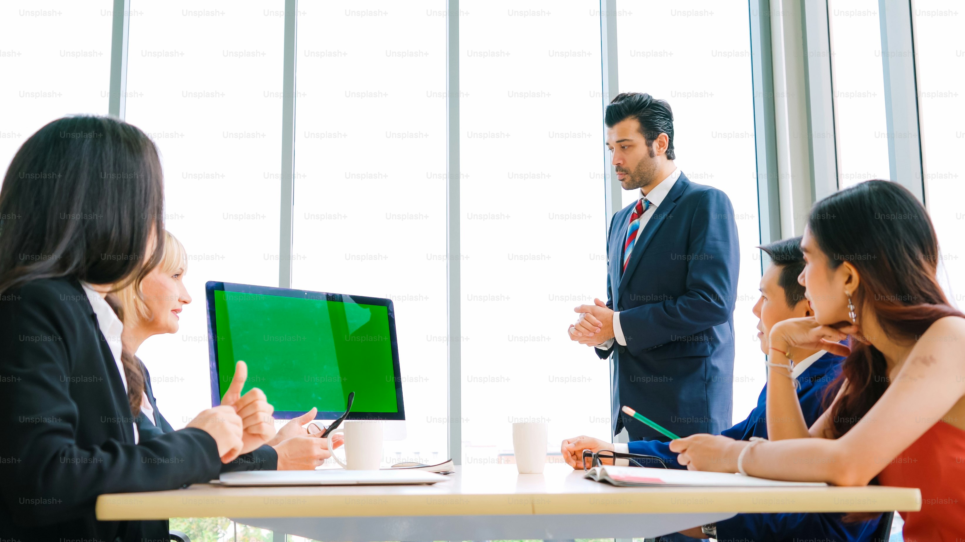 Business people in the conference room with green screen chroma key TV or computer on the office table. Diverse group of businessman and businesswoman in meeting on video conference call .