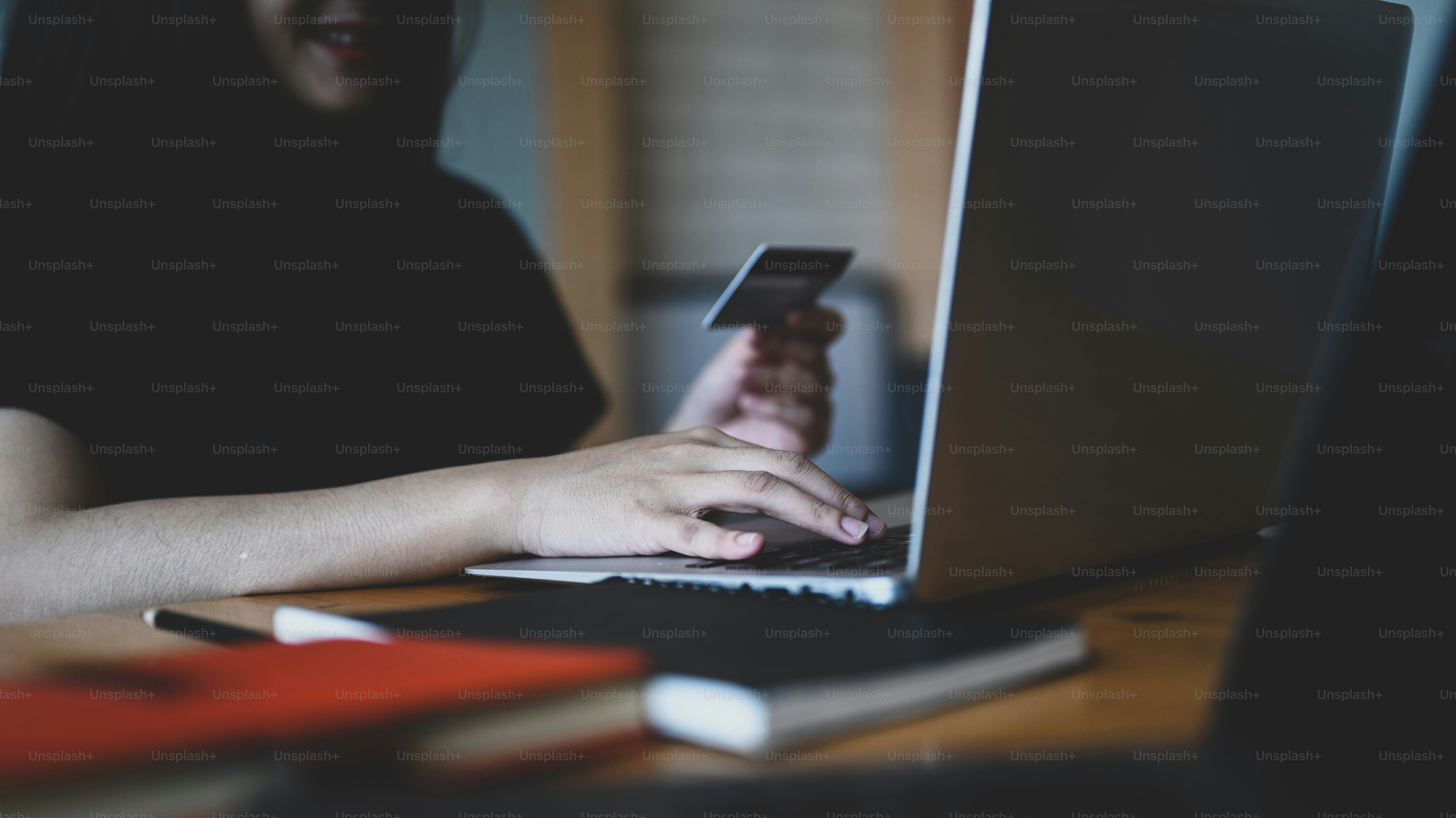 Foto wanita muda yang memegang kartu kredit dan menggunakan komputer laptop untuk belanja online atau transaksi pembayaran.