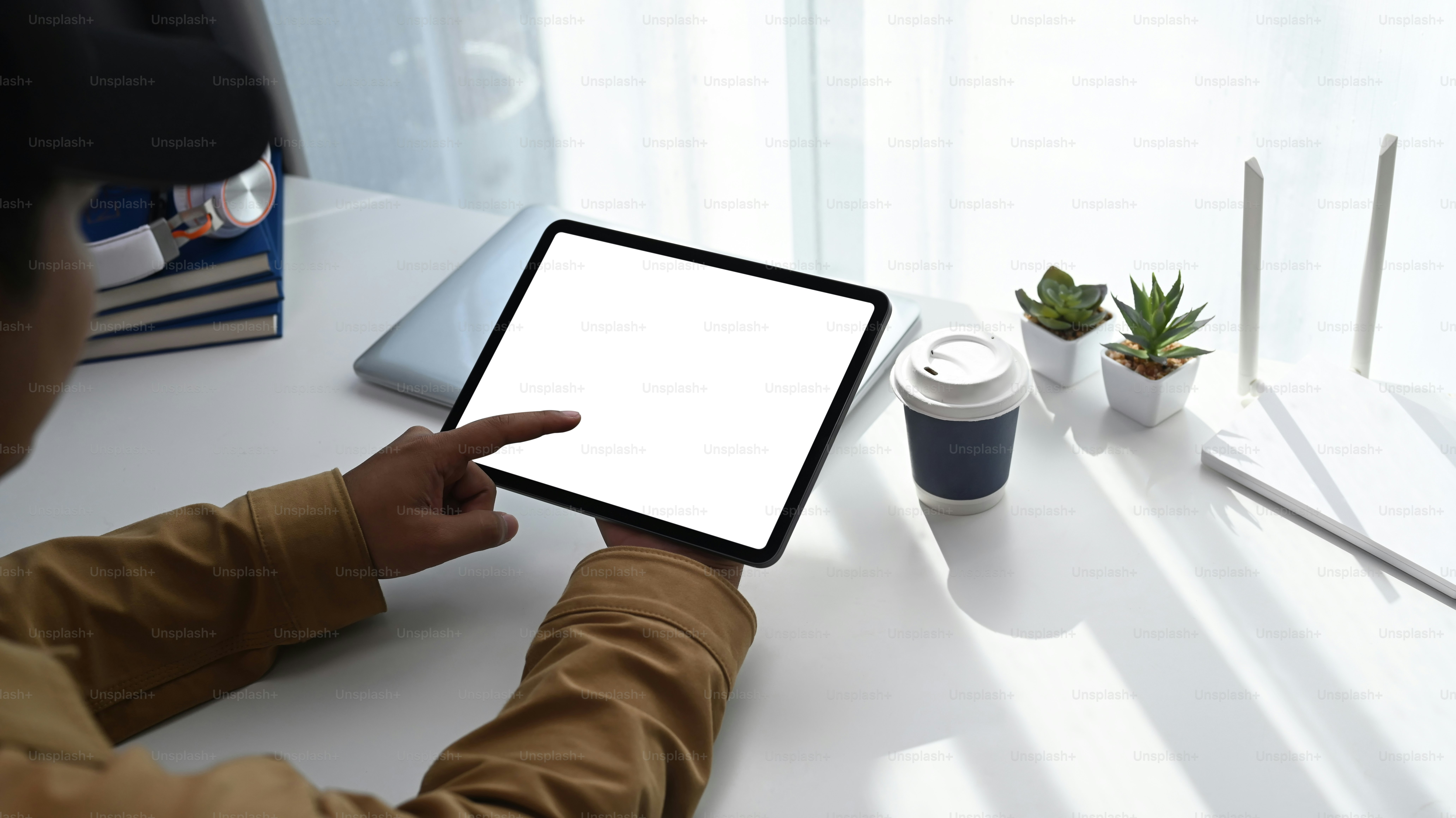 Vue rapprochée d’un jeune homme utilisant une tablette numérique pendant qu’il travaille en ligne à la maison.