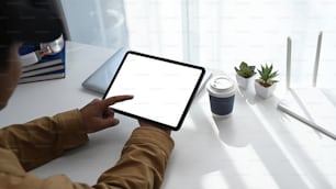 Close up view of young man using digital tablet during working online at home.