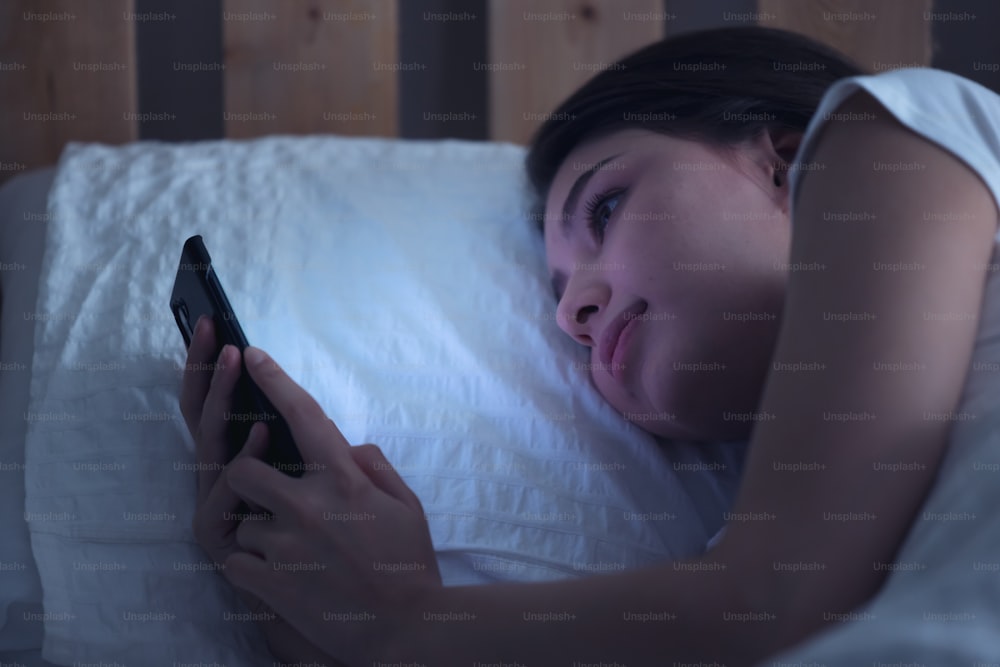 Caucasian woman using cell phone in bed
