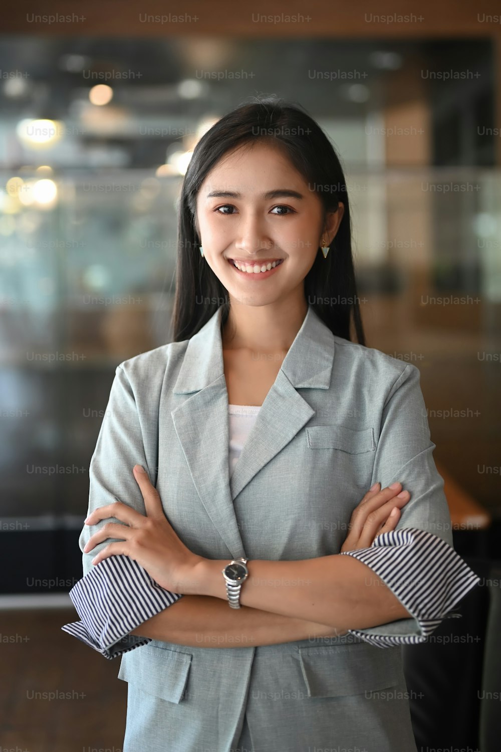 Portrait of confident businesswoman standing with arms crossed in office and smiling to camera.