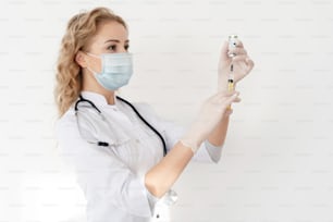 Healthcare concept. Doctor holding syringe with vaccines for children or older adults, standing in clinic. Nurse wearing in white medical coat, face mask and protective surgical gloves
