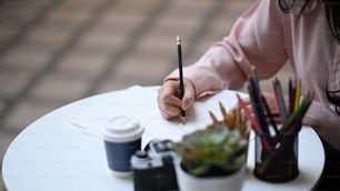Close up view of female painter holding pencils drawing draft at sketchbook at her stylish workshop.