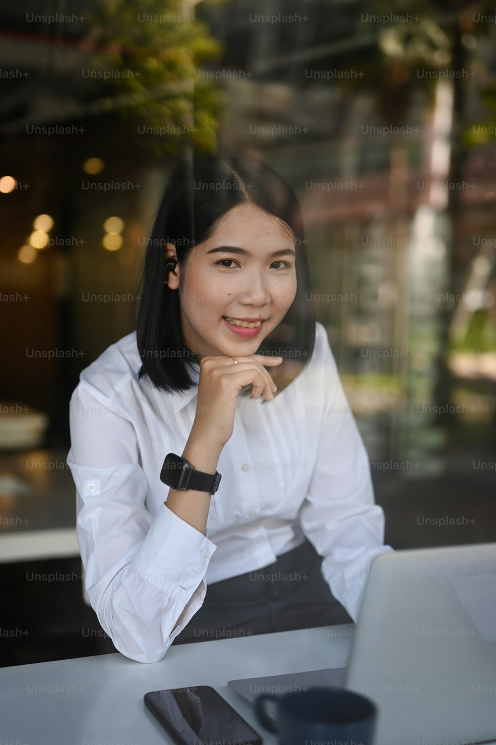 Portrait of confident businesswoman sitting in front of her laptop at her workplace and smiling to camera.