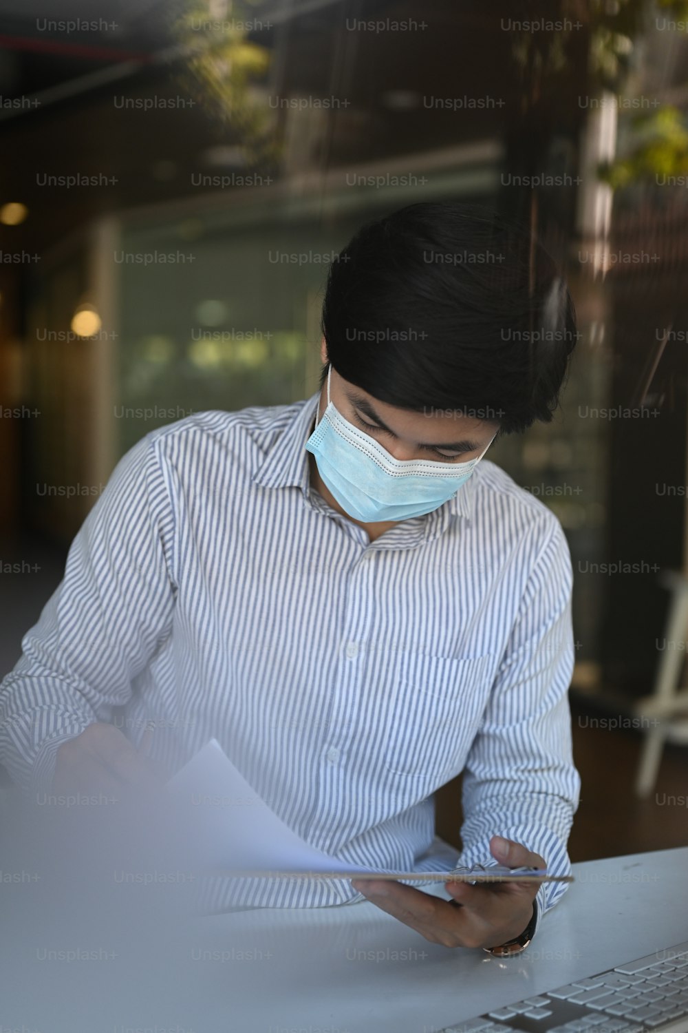 Close up view of Asian office employee man wearing protective face mask work in office.