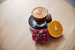 Top view of cup of coffee on plate with cookies and juicy grenade and orange are waiting for people