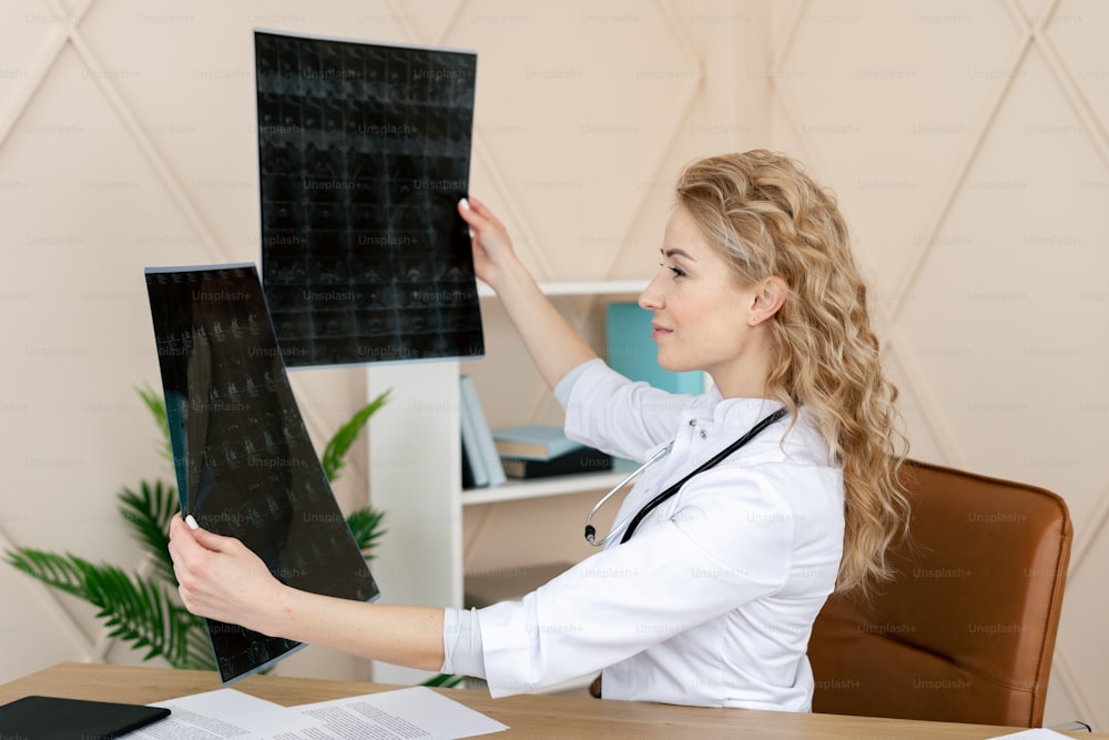Woman doctor looking at x-ray or magnetic resonance scan of the brain. Professional medic wearing in white uniform with stethoscope, sitting in modern clinic office. Health check up, insurance concept
