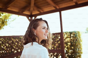 souriante élégante femme au foyer d’âge moyen en chemise blanche dans le patio.
