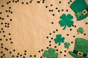 Joyeux concept de la Saint-Patrick. Composition de laïcité plate avec des chapeaux verts et des feuilles de trèfle sur fond de papier kraft. Conception de bannière de la Saint-Patrick, modèle d’affiche.