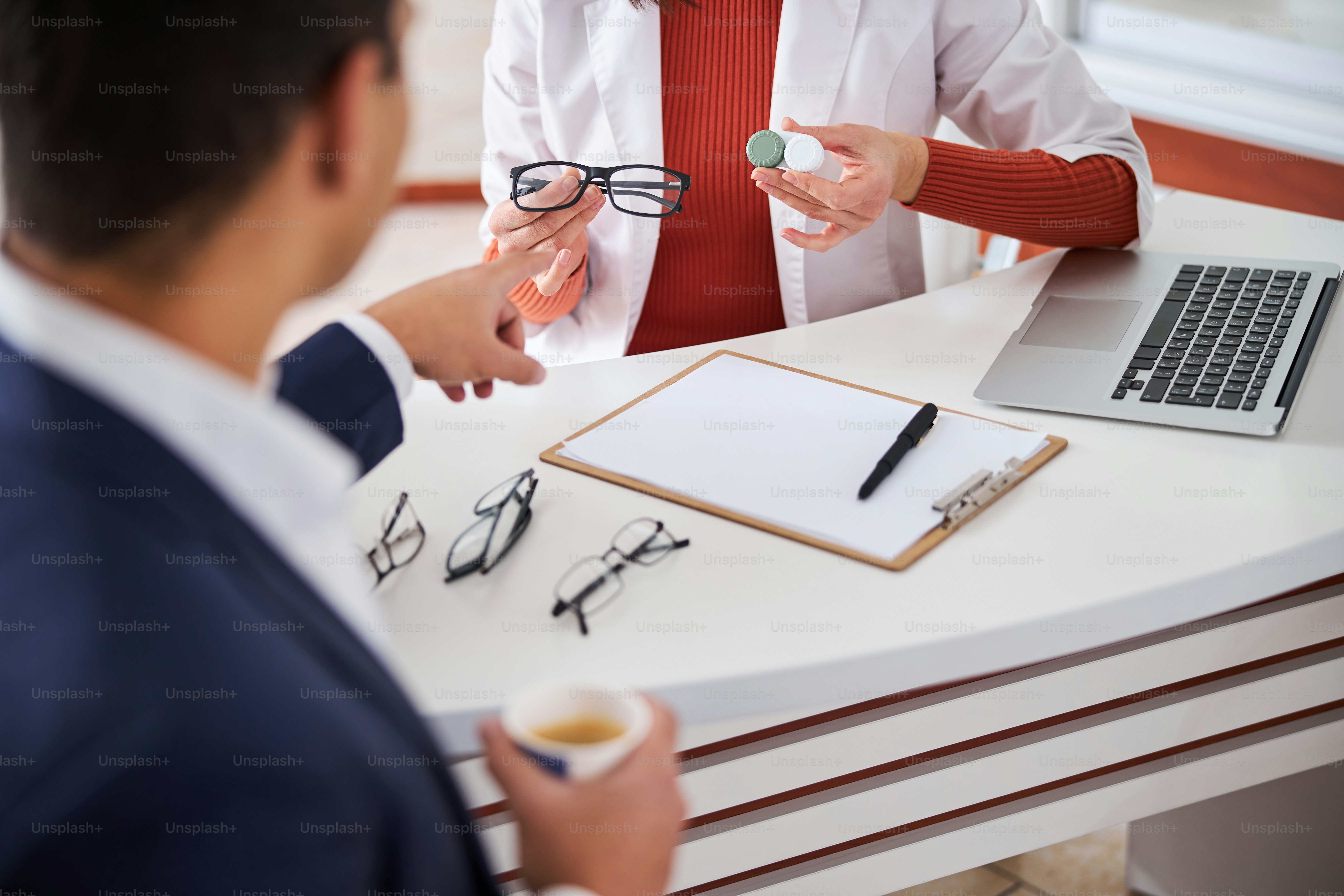 Cropped photo of a male customer choosing between a pair of glasses and contact lenses