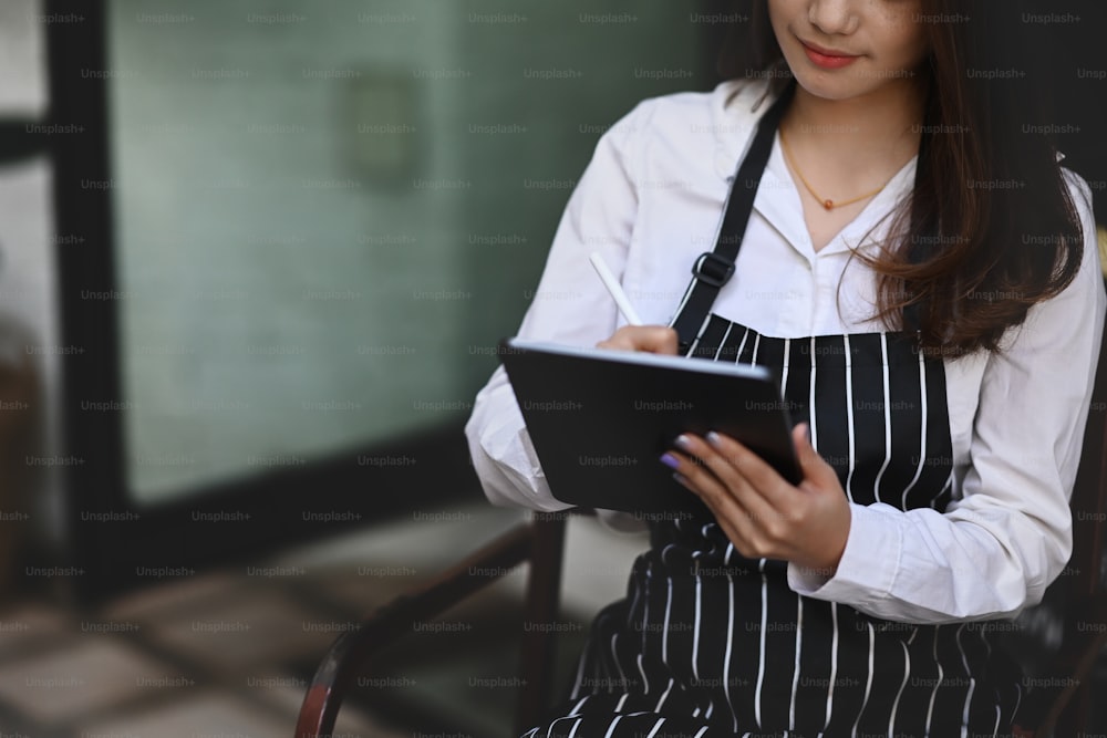 Young Asian woman barista using digital tablet receive orders from customers.