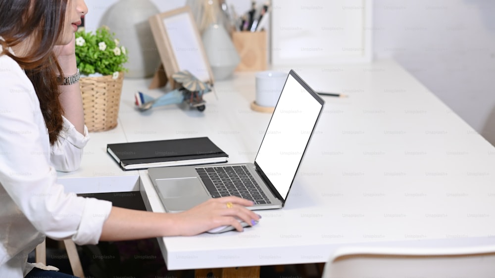 Ausschnittaufnahme einer jungen Unternehmerin, die an einem modernen Arbeitsplatz am Laptop arbeitet.