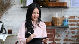 Atraente designer jovem mulher trabalhando em seu tablet no café.