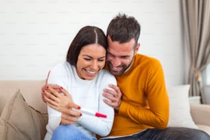We become parents. Shot of a couple feeling happy after taking a home pregnancy test. I'm pregnant Happy young couple with pregnancy test. Joyful couple with positive pregnancy shown in the test device
