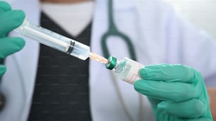 Vue rapprochée d’un médecin tenant une seringue d’injection et un vaccin.