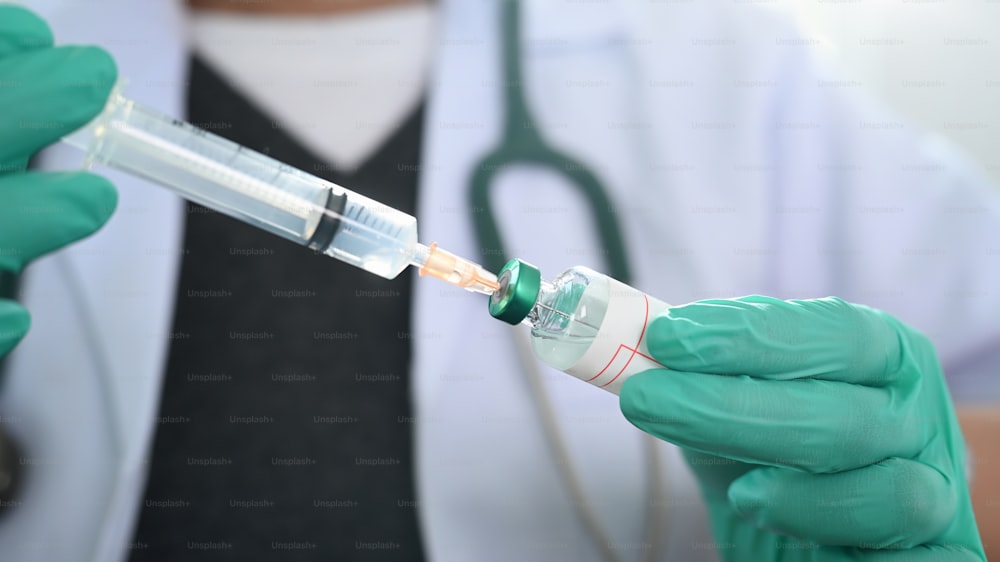 Close up view of doctor holding an injection syringe and vaccine.