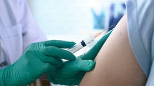 Close up view of doctor holding syringe and giving injection to woman at hospital.