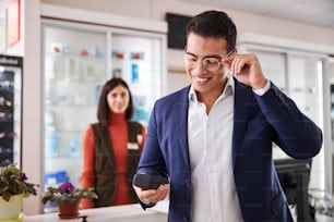 Joyous elegant man in round prescription glasses looking at the eyewear case in his hand