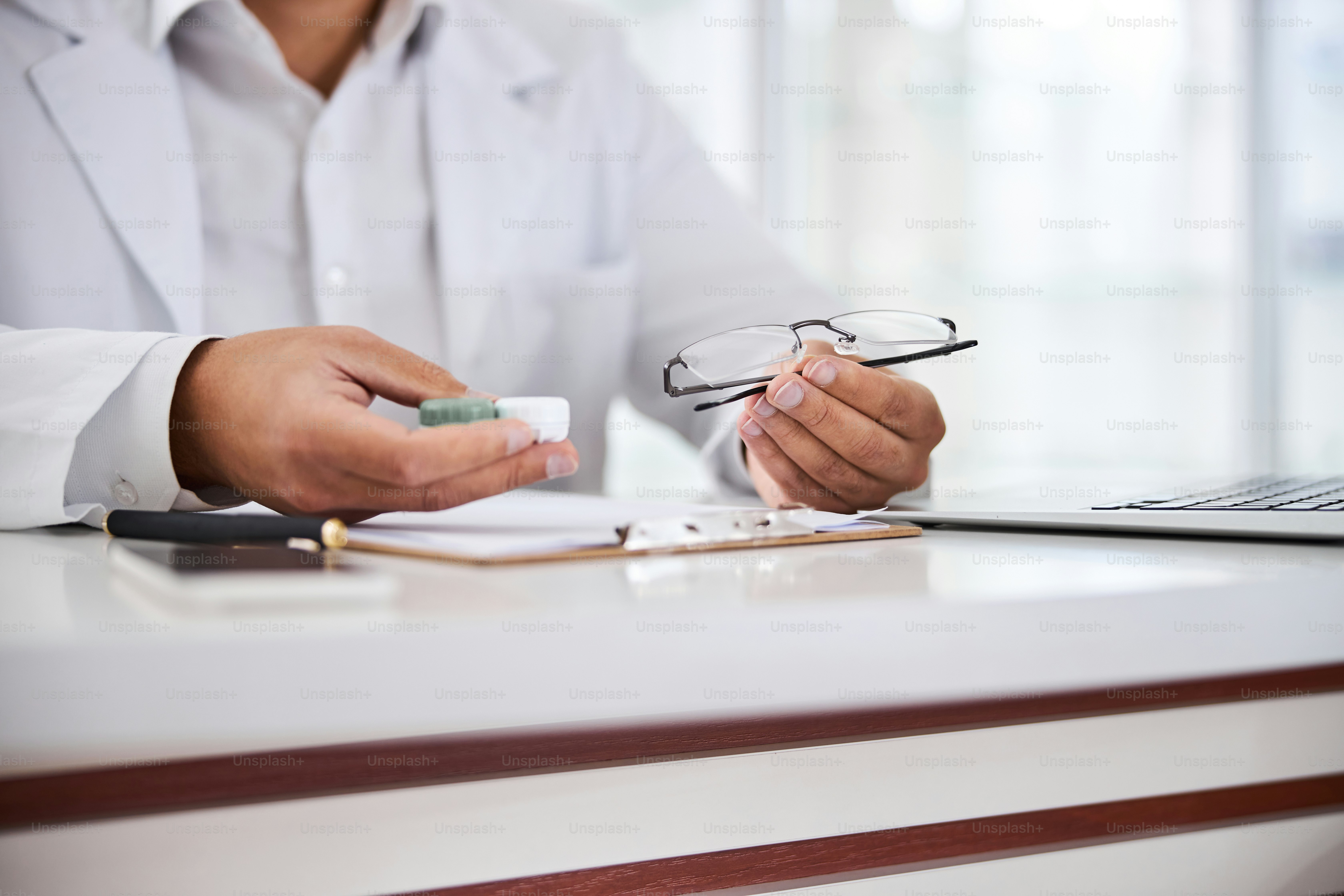 Cropped photo of an optician showing a lens case and spectacles in ...