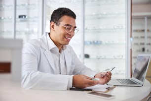 Pleased optical dispenser examining a pair of spectacles and the lens case in his hands