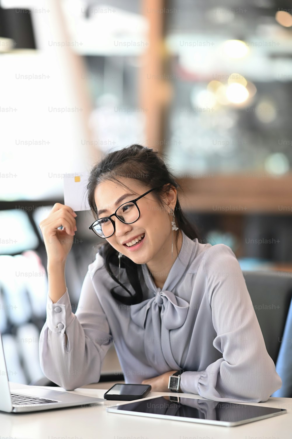 Portrait of cheerful young woman in eye glasses using laptop and holding credit card making payment online or online shopping.