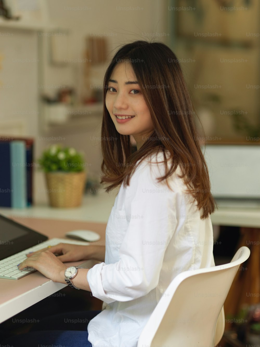 Portrait of female office worker smiling to camera while sitting at workplace