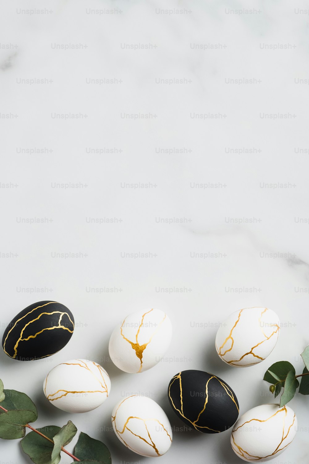 Maquette de bannière verticale de joyeuses Pâques. Oeufs de Pâques de luxe décorés de feuilles d’or et d’eucalyptus sur fond de marbre. Pose à plat, vue de dessus.