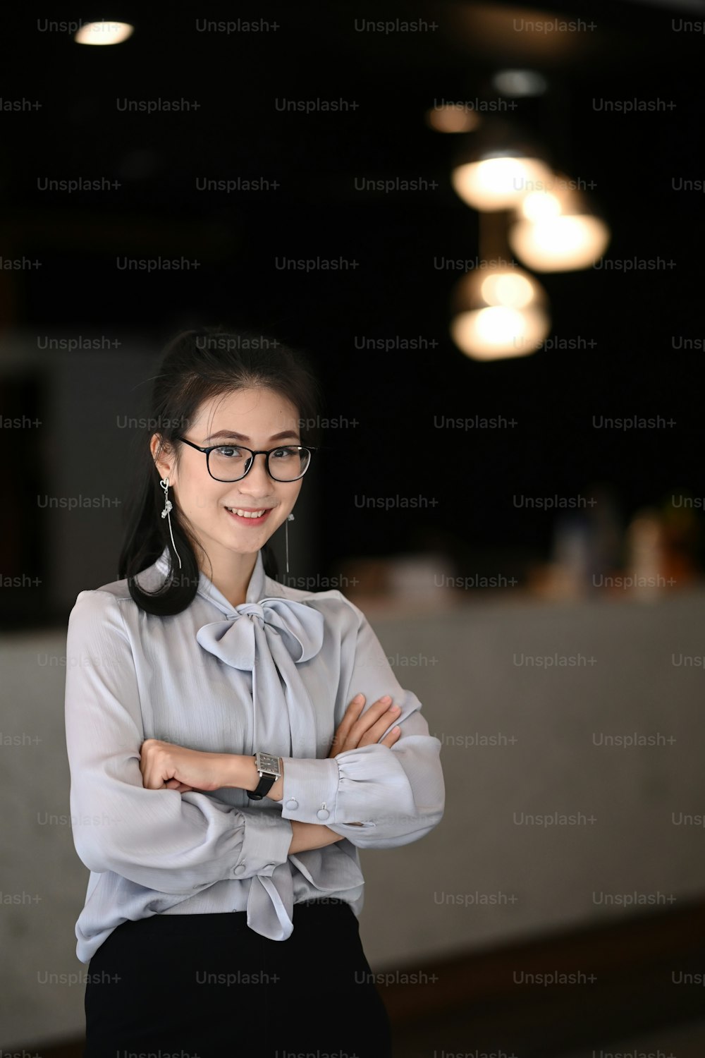 Portrait of confidence businesswoman standing with arms crossed in office building.