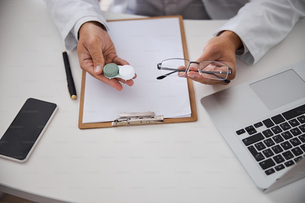 Cropped photo of an optician showing a lens case and spectacles in front of the camera