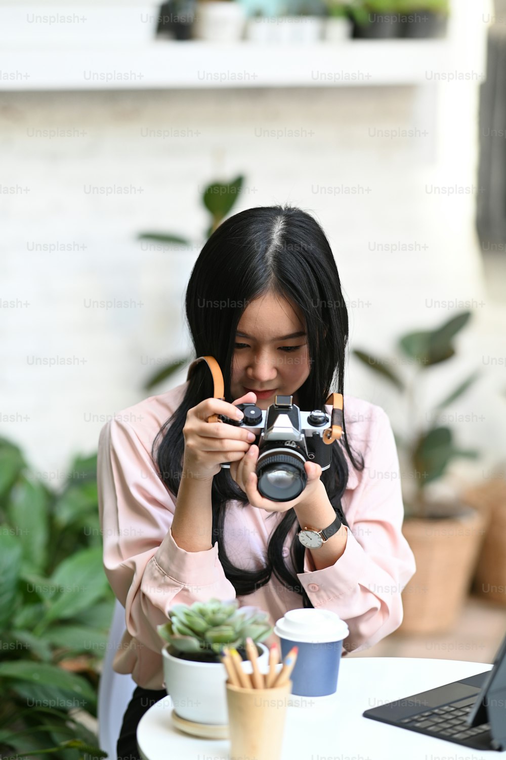 Portrait of young female photographer checking photo on camera while sitting at outdoor cafe.